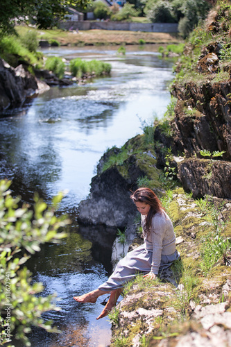 Young woman sat on river bank photo