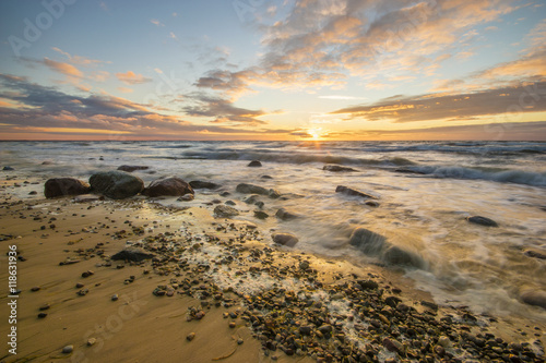 Sea landscape at sunset, sandy beach and cliff,waves breaking on the shore