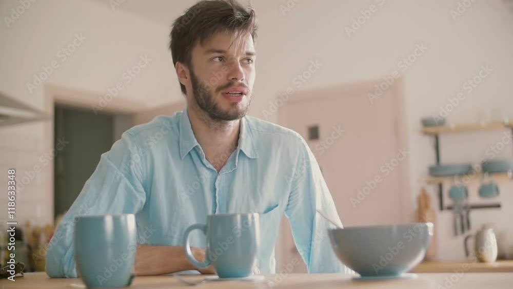 Young man having a conversation at the kitchen table. Slow motion Young man having a conversation at the kitchen table. Slow motion
