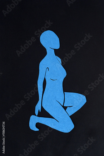 Cut-out blue paper female figure on black background