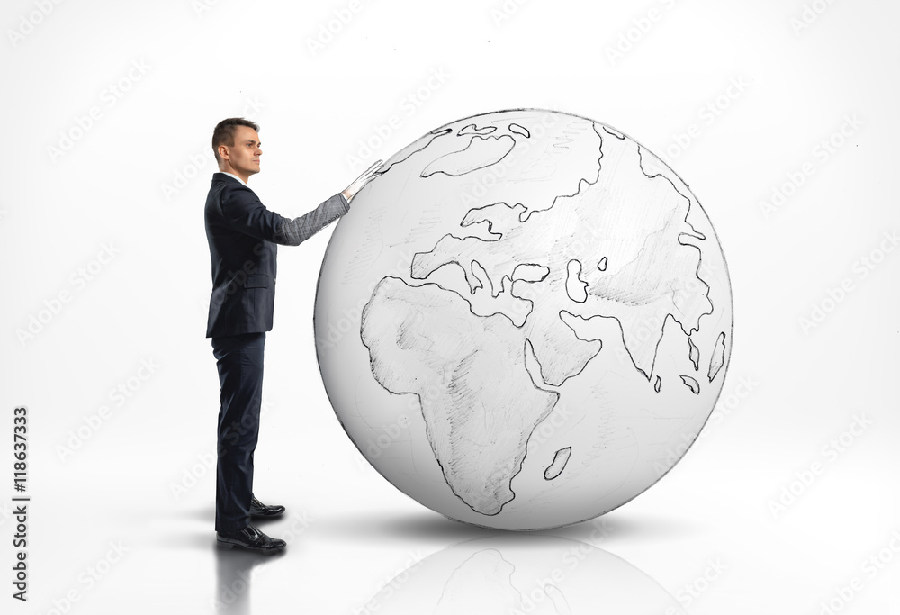 Businessman standing next to a large world globe Businessman standing next to a large world globe