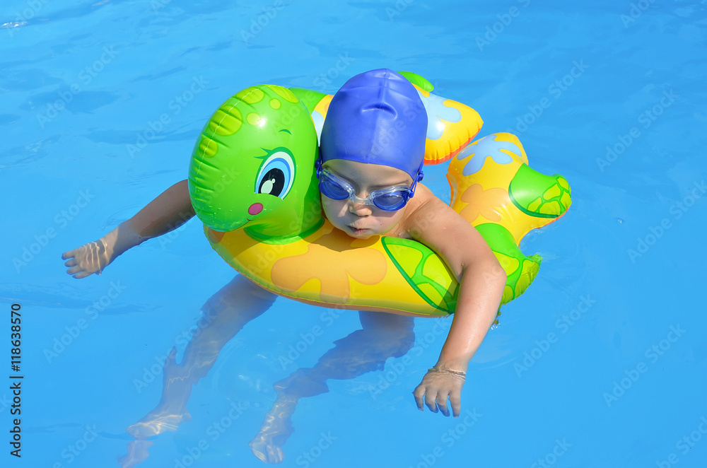 Little girl in the swimming pool with a rubber ring.