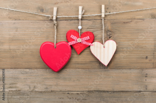 Wooden hearts hanging on a clothesline with clothespins.