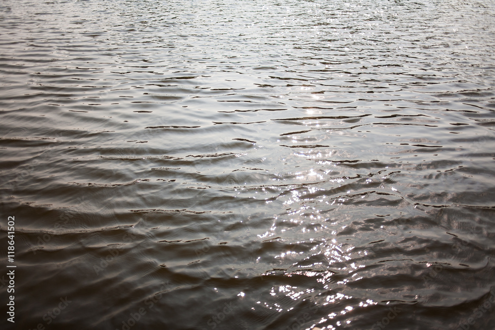 Calm surface of real river water with sunlight reflection. Horizontal color photo. Shiny water background. Calm surface of real river water with sunlight reflection. Horizontal color photo. Shiny water background.