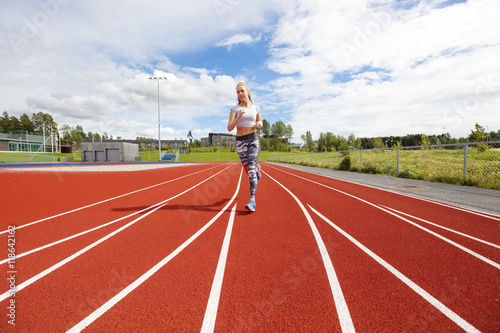 Fast athletic female runner on outdoor running track