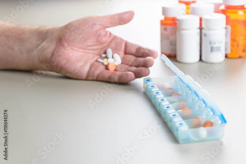 Elderly man sorting daily medication into a pill box.