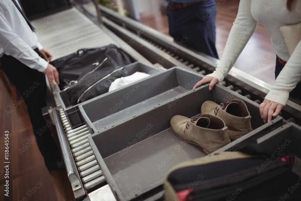 Woman putting shoes into tray for security check Woman putting shoes into tray for security check