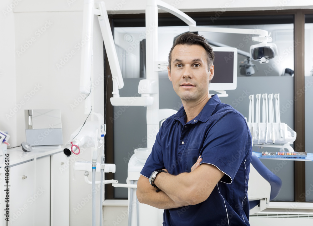 Confident Dentist With Arms Crossed At Clinic
