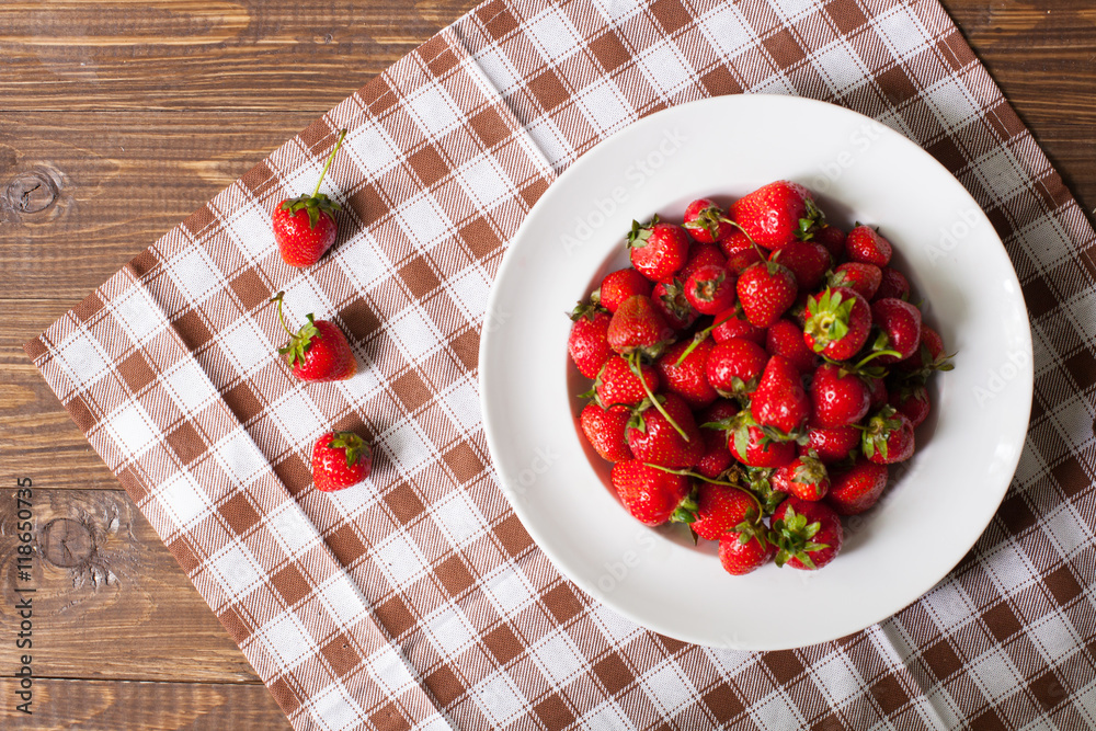 Strawberries on the plate and on the tablecloth Strawberries on the plate and on the tablecloth