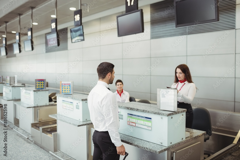 Airline check-in attendant checking passport of passenger Airline check-in attendant checking passport of passenger