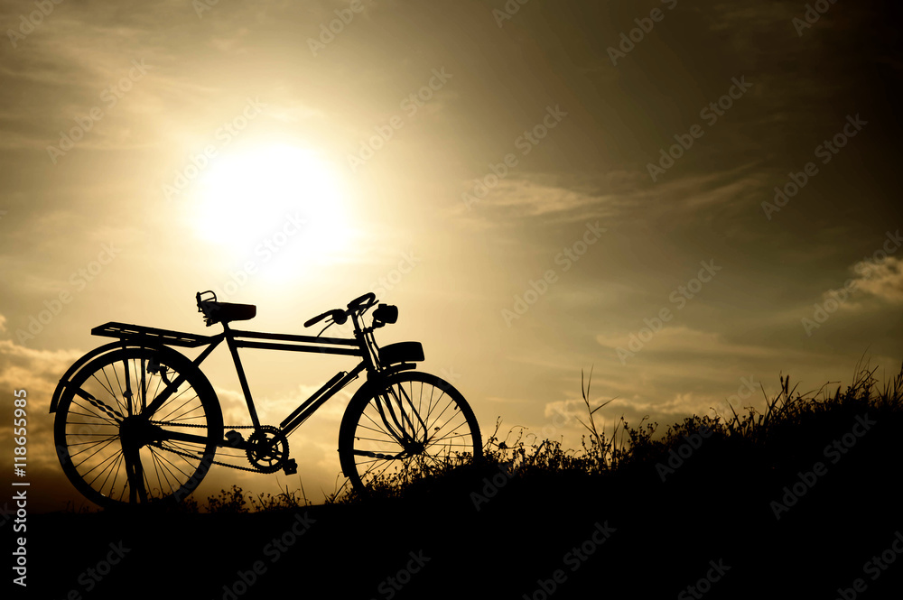 Obraz premium silhouette of a retro bicycle. parked in a meadow in evening, th