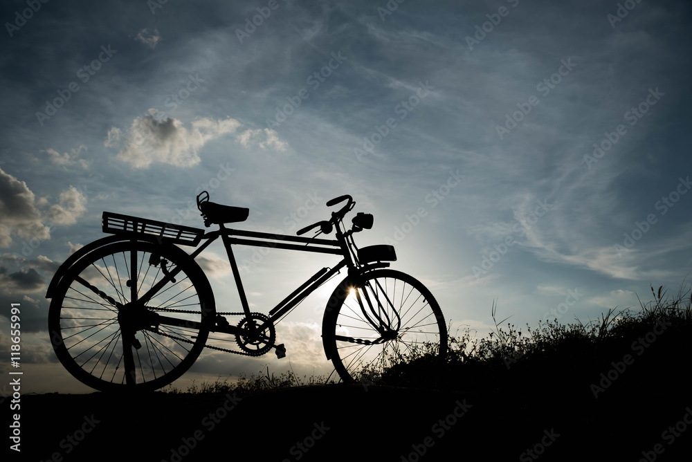 Obraz premium silhouette of a retro bicycle. parked in a meadow in evening, th