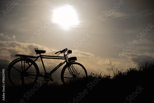 silhouette of a retro bicycle. parked in a meadow in evening, th © stcom