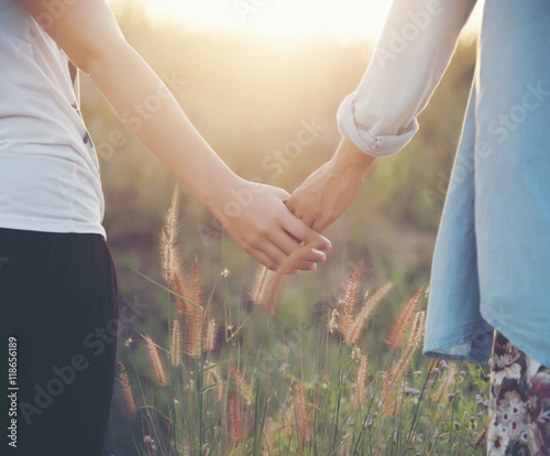 A young couple holding hands. In Nature sunrise