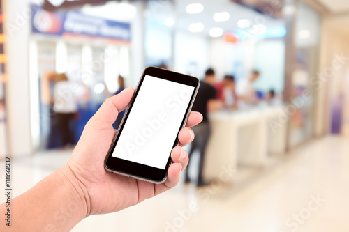 female hand holding the phone tablet on blurred in shop counter service background;Transactions by phone concept photo