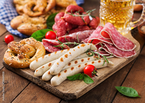 Glass of beer  pretzels and various sausages on wooden background. Oktoberfest.