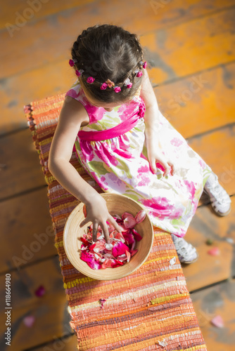 Beautiful little girl whearing dress with roses and roses wreath playing outdoor with roses petals photo