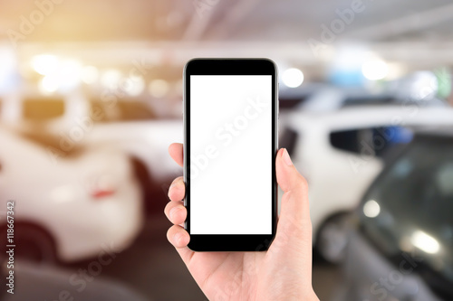 Smart phone with white screen in hand on Blur car parking background