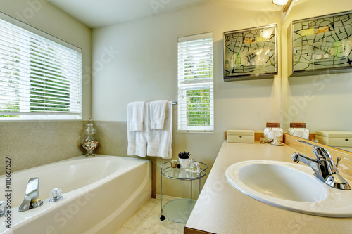 Bathroom interior with white bath tub  vanity cabinet and tile floor.