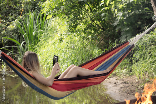 girl in a hammock with a phone in his hand