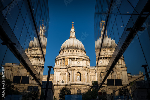 St Paul’s cathedral seen from a narrow alley enclosed by glass buildings and reflecting in the shiny surface at morning dawn