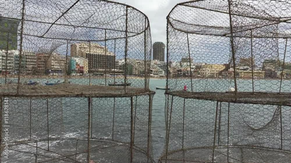 A panoramic view of Las Canteras beach through a group of fishing baskets A panoramic view of Las Canteras beach through a group of fishing baskets