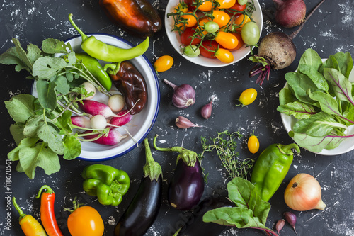 Foto Fresh vegetables - radishes, eggplant, pepper, tomatoes, onion, garlic on a dark wooden background