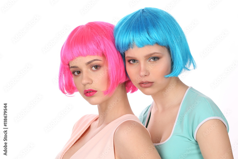 Ladies in colorful wigs and T-shirts posing. Close up. White background