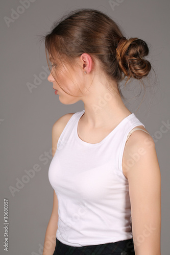 Model in white singlet standing profile. Close up. Gray background