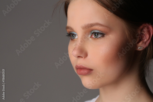 Girl with makeup looking away. Close up. Gray background