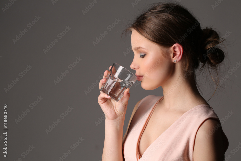 Girl drinking water. Close up. Gray background Girl drinking water. Close up. Gray background