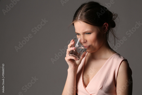 Girl drinking water is dissatisfied. Close up. Gray background