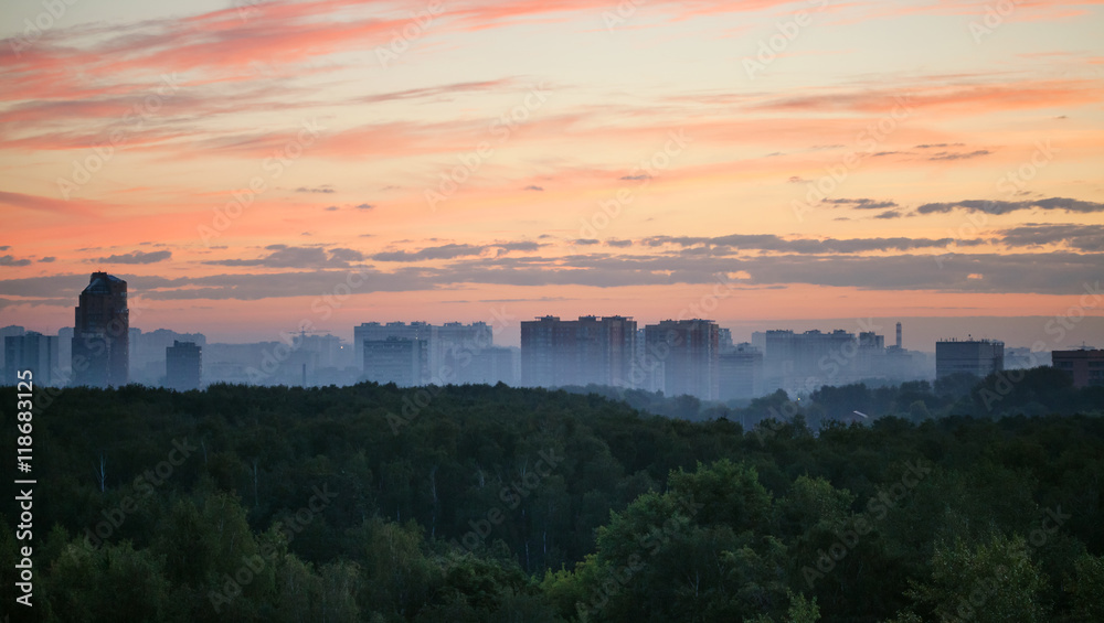 early sunrise and morning mist over woods and city
