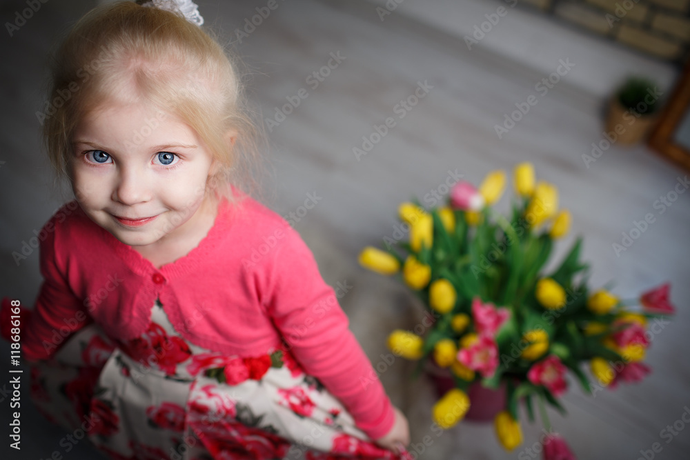 Fototapeta premium Portrait of a beautiful little girl with flowers on background of brick wall