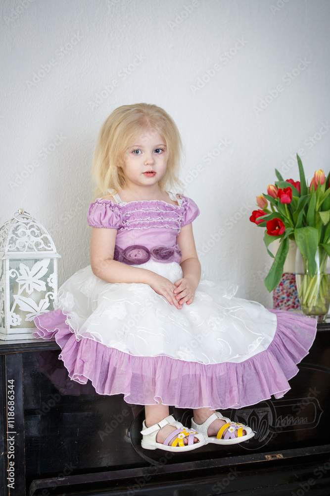 Portrait of a little girl with a beautiful dress near the piano Portrait of a little girl with a beautiful dress near the piano