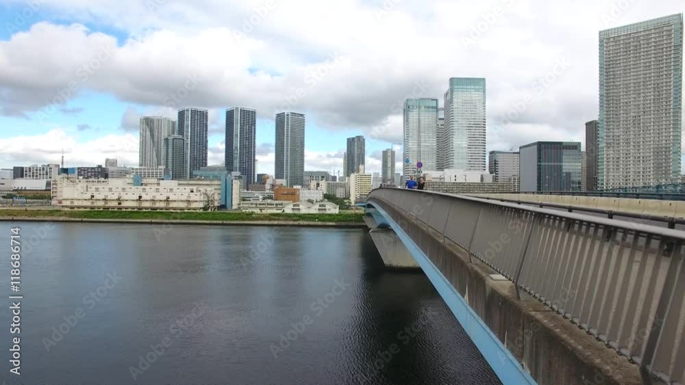 Caucasion and Japanese runner training on bridge Tokyo Drone aerial shot front view city background 