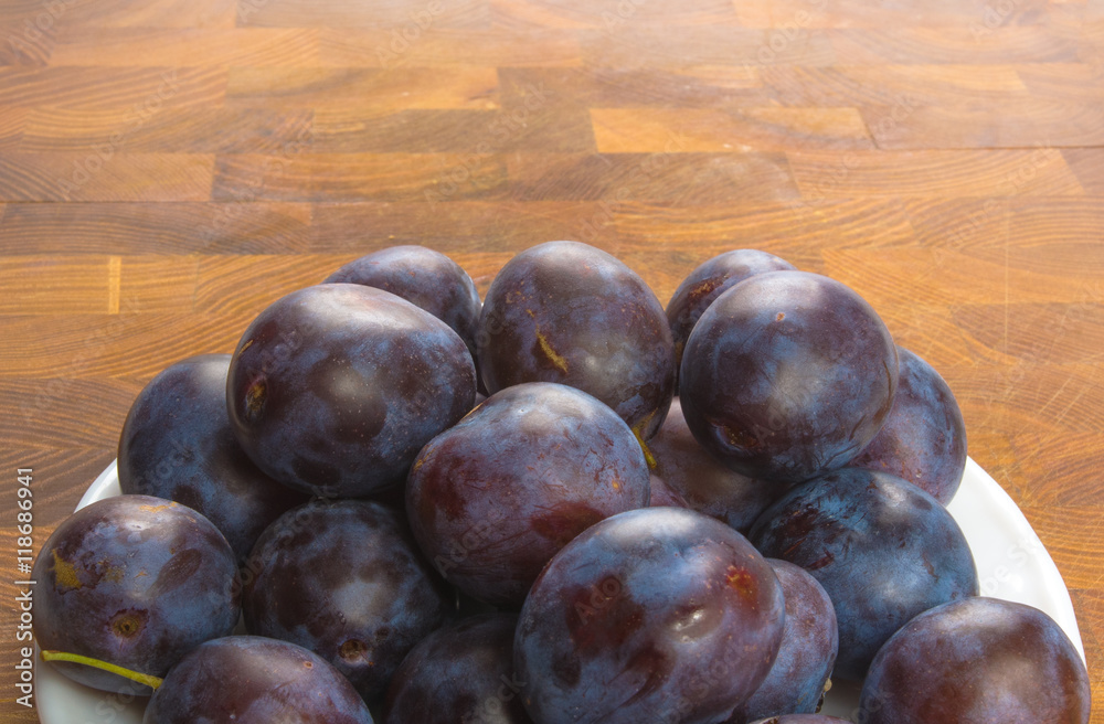Fototapeta premium small plums on a white saucer