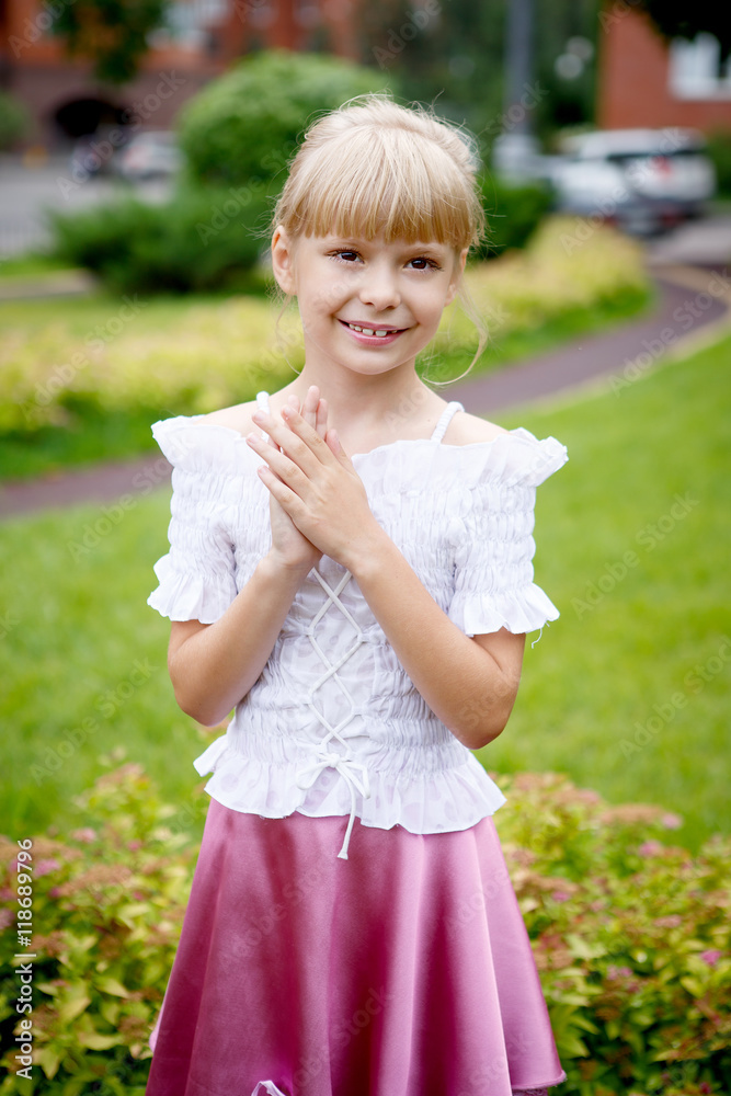 Portrait of beautiful little girl in a white blouse with a pink skirt in the Park Portrait of beautiful little girl in a white blouse with a pink skirt in the Park
