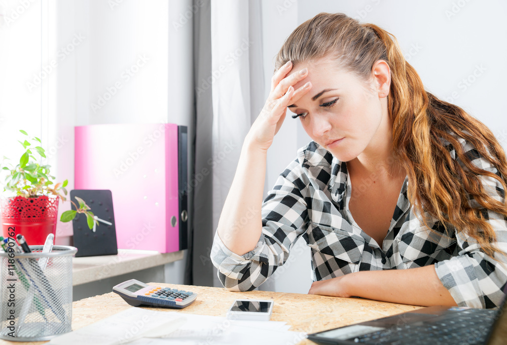 Stressed and thinking woman in home office using laptop Stressed and thinking woman in home office using laptop