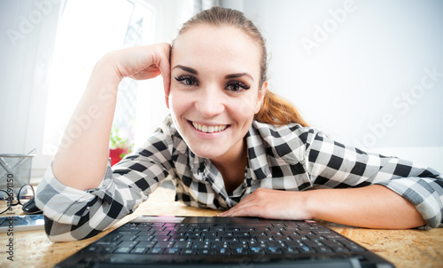 Smiling woman using laptop in home office, view from webcam