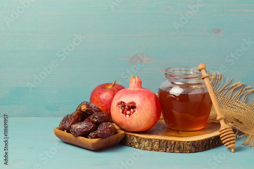 фотографія Honey, pomegranate, apple and dates on wooden board