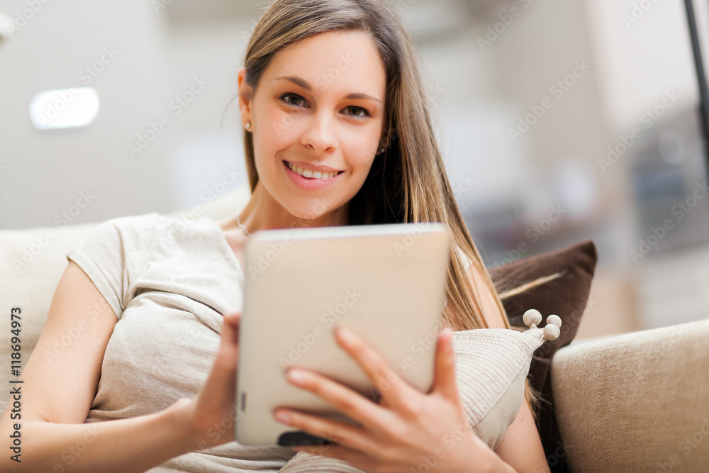 Portrait of a smiling young woman using a tablet computer in her apartment Portrait of a smiling young woman using a tablet computer in her apartment