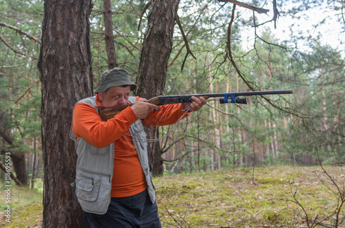 Senior hunter aim rifle in pine forest