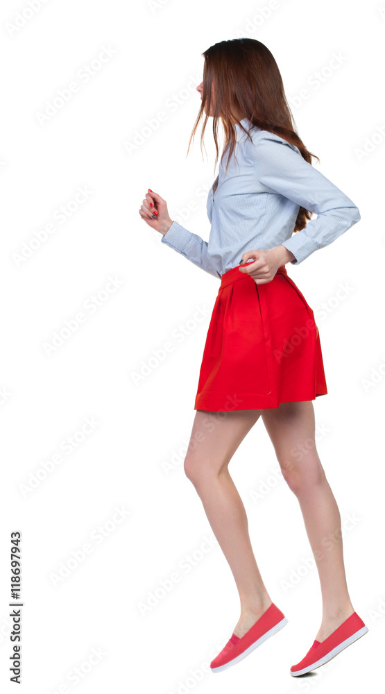 side view of running woman. beautiful girl in motion. backside view of person. Rear view people collection. Isolated over white background. Long-haired brunette in red skirt runs in the side. side view of running woman. beautiful girl in motion. backside view of person. Rear view people collection. Isolated over white background. Long-haired brunette in red skirt runs in the side.