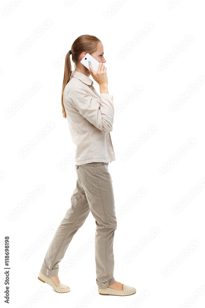 side view of a woman walking with a mobile phone. back view ofgirl in motion. backside view of person. Rear view people collection. Isolated over white background. Skinny girl in white denim suit side view of a woman walking with a mobile phone. back view ofgirl in motion. backside view of person. Rear view people collection. Isolated over white background. Skinny girl in white denim suit