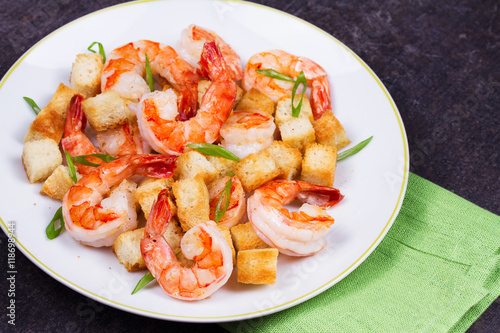 Shrimp with crispy croutons and scallions in white plate