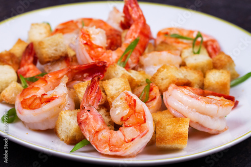 Shrimp with crispy croutons and scallions in white plate