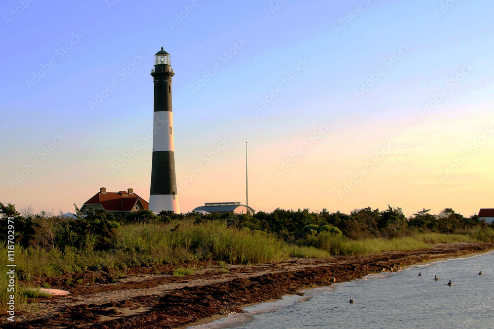 The Fire Island Lighthouse taken from behind on a dock, at dusk