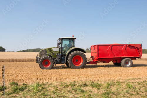 Tractor with a red trailer carrying grain