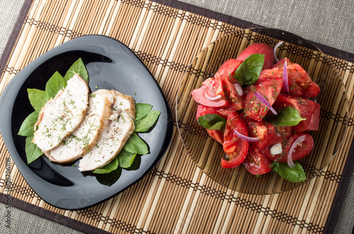 Chicken meat decorated with green leaves of basil and tomato sal photo